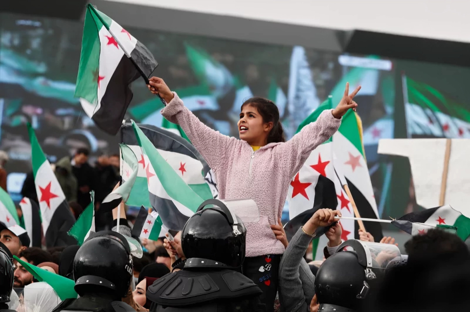 A Girl waving the new Syrian flag in a crowd